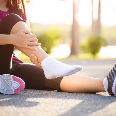 Ankle sprained. Young woman suffering from an ankle injury while