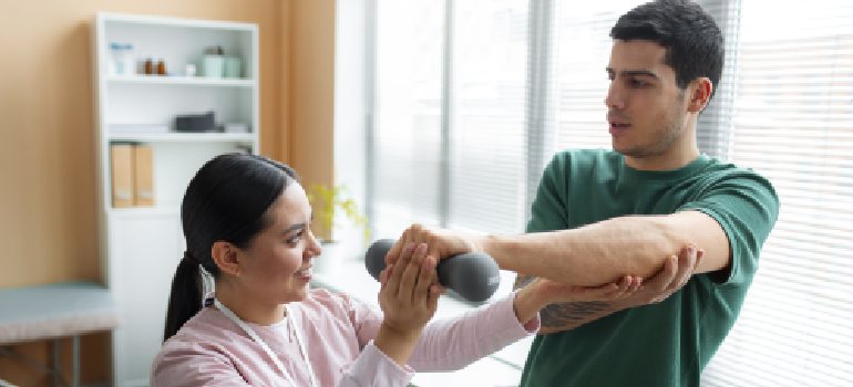 doctor-helping-patient-during-rehabilitation (1) (2)