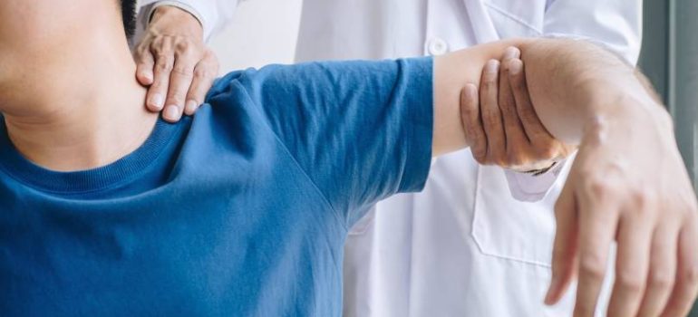 Physiotherapist assisting a patient with frozen shoulder physiotherapy treatment.