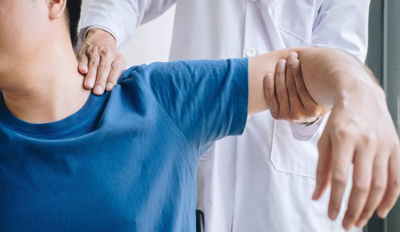 Physiotherapist assisting a patient with frozen shoulder physiotherapy treatment.