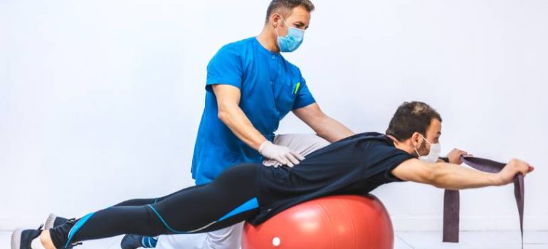 Physiotherapist demonstrating back strengthening exercise to patient
