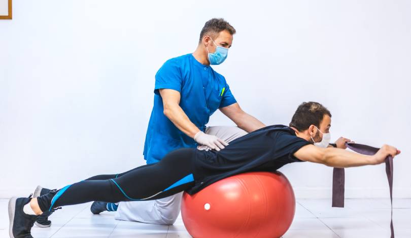 Physiotherapist demonstrating back strengthening exercise to patient