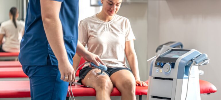 patient-working-with-a-physiotherapist-on-a-specialized-strength-machine-after-knee-surgery